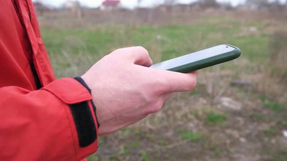 A Man Uses a Smartphone Surf the Internet on the Street