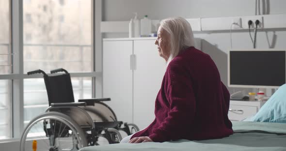 Back View of Senior Woman Sitting in Hospital Bed