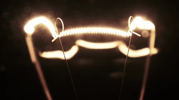 Tungsten Filament in a Glass Lamp Closeup in Slow Motion on Black Background