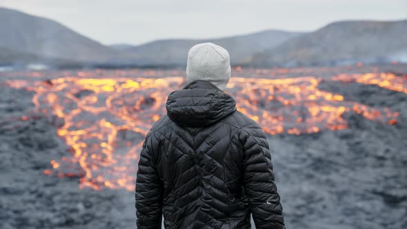 Man Looking Out Over Flowing Lava In Burning Landscape