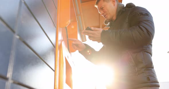 Man Looking Into Mobile Phone and Dialing Code on Keypad of Postal Machine  Movie