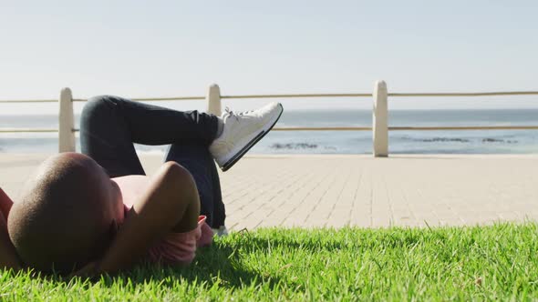 Video of happy african american boy lying on grass, relaxing by sea