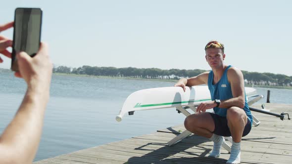 Male rower taking picture of male rower next to the boat