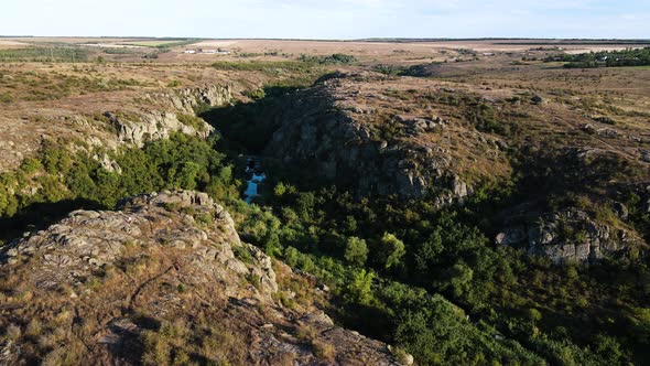 A Narrow Rocky Canyon with Trees and a Small River