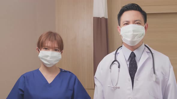 Asian doctor and nurse put protective surgical mask on to prevent covid virus pandemic in hospital.