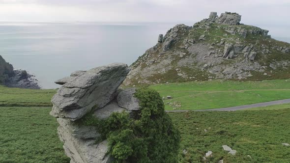 Aerial tracking from right to left revealing a rocky stack in the foreground and the valley of rocks