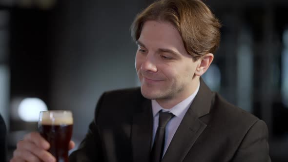 Positive Happy Caucasian Man Toasting Pint of Beer Looking at Camera Smiling