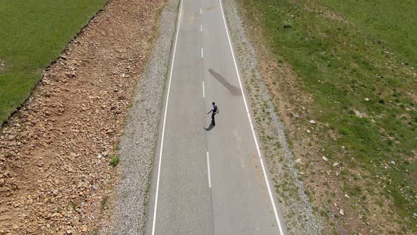 Guy in Summer in Black Clothes Descends From the Mountain on a Skateboard