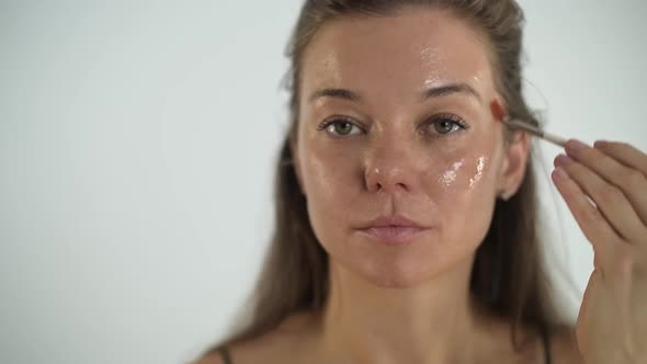 A Young Beautiful Girl Applies a Transparent Moisturizing Mask to Her Face