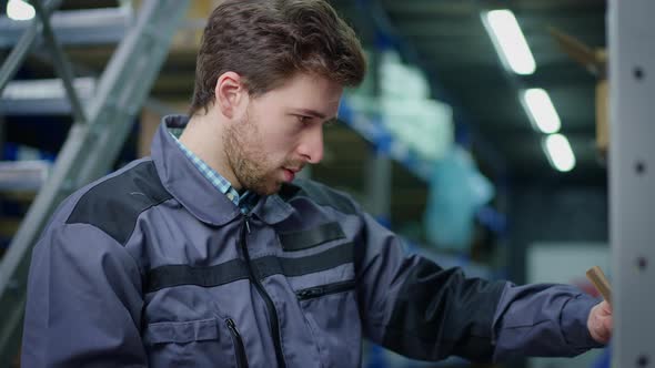 Brunette Man Scanning Barcode on Cardboard Box with Scanner in Urban Industrial Warehouse