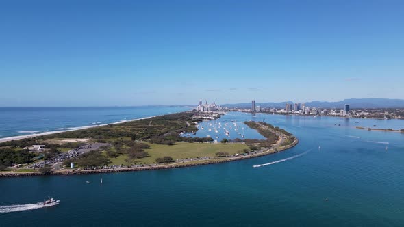 High fasting drone view travelling over a man-made ocean inlet towards an urban boat harbor with a m