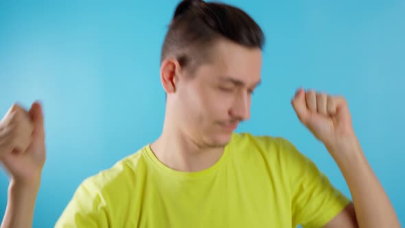 Funny Guy in a Yellow Tshirt on a Blue Background Dancing Having Fun