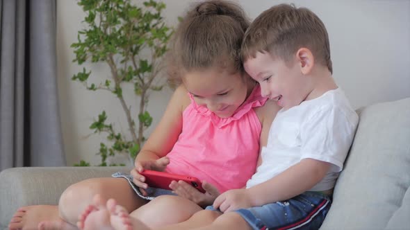 Happy Children Playing at Home Relaxing Use a Smartphone Cuddling Sit on Sofa Daughter and Son,look