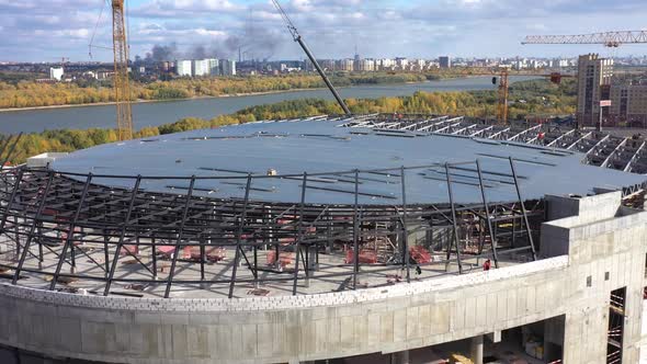 Flat Roofed Stadium Building and Cranes Near Calm River