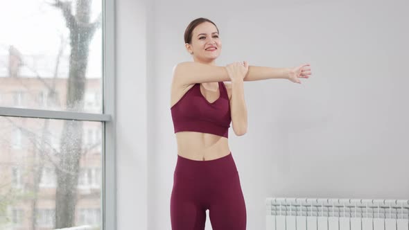 a Woman in a Burgundy Tracksuit Exercises in a Gym