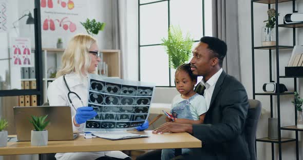 Woman-Doctor Explaining X-ray Results of Small Girl's Lungs to Girl's Father