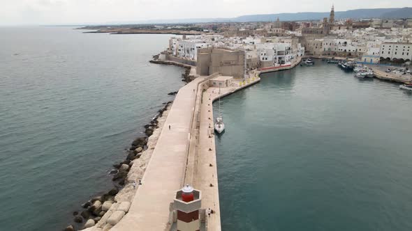 Aerial drone shot pushing from a lighthouse to a castle wall. Monopoli, Italy