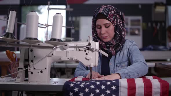 Woman wearing headscarf sewing American Flag