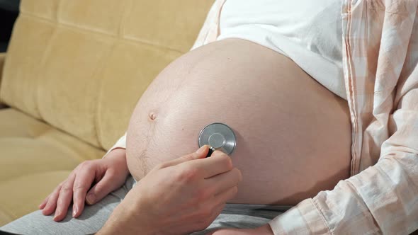 Unrecognizable Man Listens to the Baby in the Belly of a Pregnant Woman Using a Phonendoscope