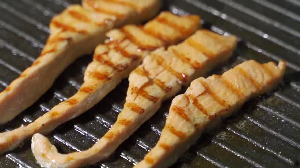 Homemade Fish Meal. Piece of Salmon or Trout Fillet Frying on Grilled Pan.