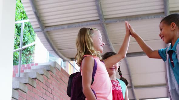 School kids giving high five to each other in school corridor