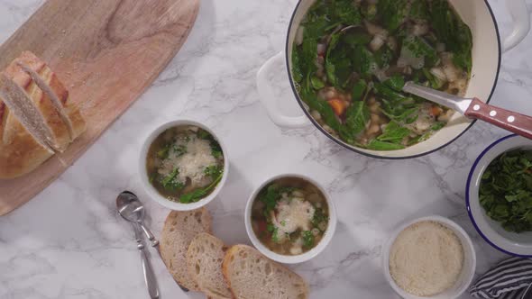 Serving  vegetarian white bean soup in a white bowls