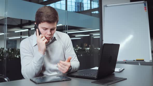 Analyst Checking Statistics and Talking on Phone