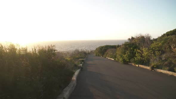 Asphalt Road Leading Down to Coastline near Mediterranean Sea in Malta on Sunny Evening