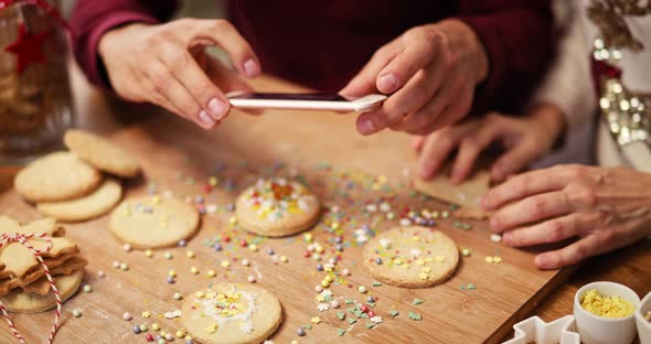 Handheld view of man photographing Christmas cookies in the kitchen