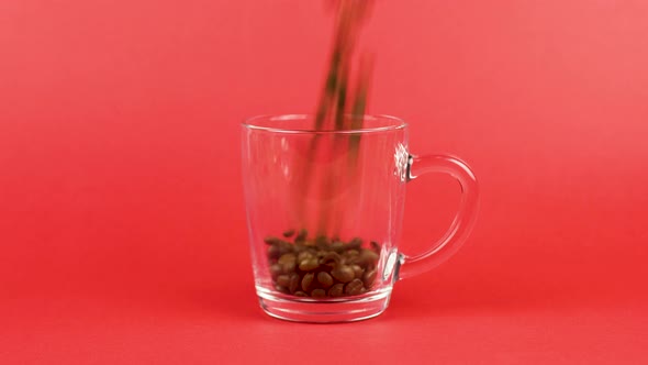 Coffee Bean Quickly Pour, Transparent Glass Cup, Red Background. Morning Concept