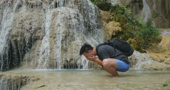 Man Washing His Face In Deep Forest Waterfall