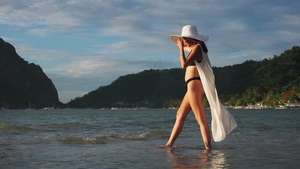 Woman In Bikini And Sun Hat Walking In Sea