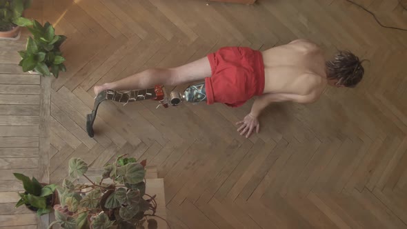 Young Man with Modern Leg Bioprosthesis Does Yoga on Floor