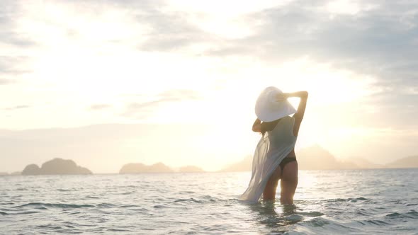 Woman In Thong And Sun Hat In Sea At Sunset