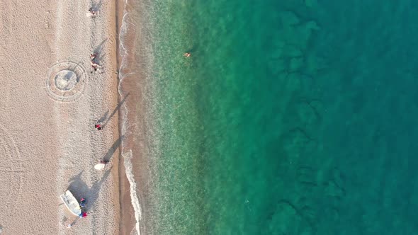 Aerial Shot of People Relaxing at an Empty Beach with Tranquil Sea Water