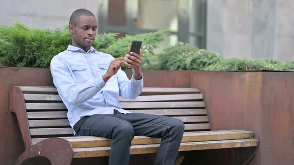 Attractive African Man Using Smartphone Outdoor