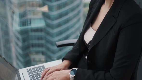 Close-up Portrait of a Business Woman Working on a Laptop While Sitting By a Window on a High Floor