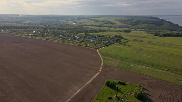 Aerial Photography of a Plowed Field Next to a Settlement