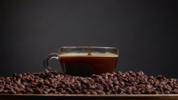 Fragrant Coffee Drops Falling in Espresso Cup Close Up