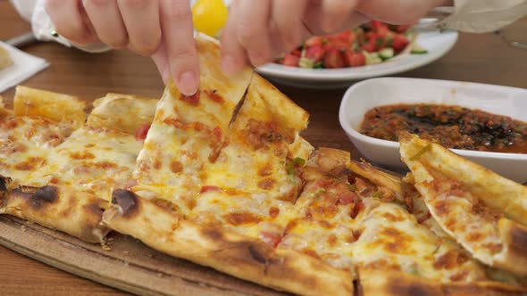 Woman Is Taking a Slice of Khachapuri From Wooden Board To Eat, Hands Closeup.