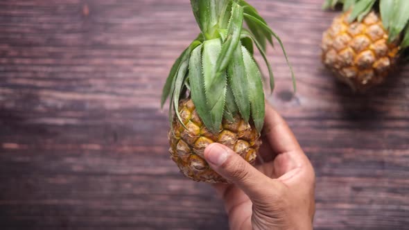 Holding Fresh Pineapple in Bowl on Table