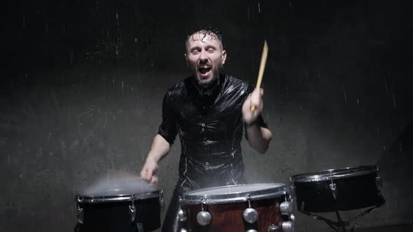 The Drummer on the Drum Wooden Sticks and Water Drops Flying in All Directions.