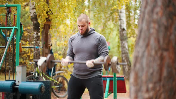 A Man Bodybuilder Pumping His Hands with the Self made Dumbbells Training on the Outdoors Sports