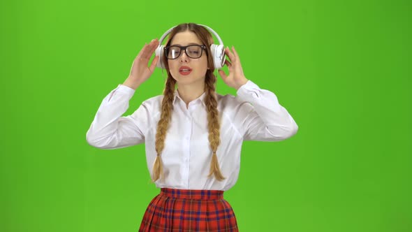 Girl in Glasses Listens To Music on Headphones . Green Screen