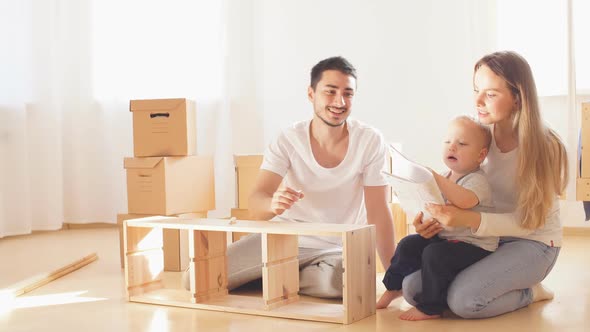 Family Reading Instruction and Assemble Furniture Together at Living Room of New Apartment Pile