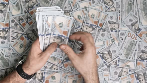 Man Counting USD Cash Dollars on Pile of Money Background