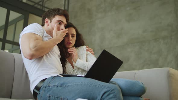 Portrait of Scared Couple Watching Laptop Computer at Home in Slow Motion.