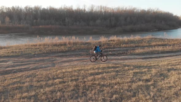 Aerial View of a Cyclist Riding on His Bicycle in Mountain at Sunset