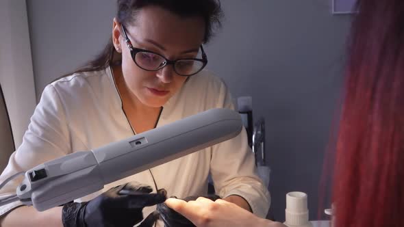 Manicurist in the Glasses Is Working on the Nails of the Female Client