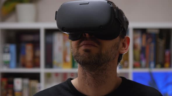 Close-up of a bearded man wearing VR glasses on his head. Home interior